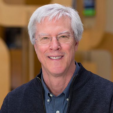 portrait of man in blue jacket with white hair